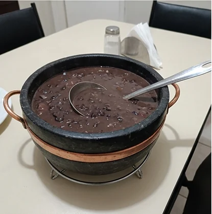 Feijão servido em uma panela de pedra sabão sobre a mesa